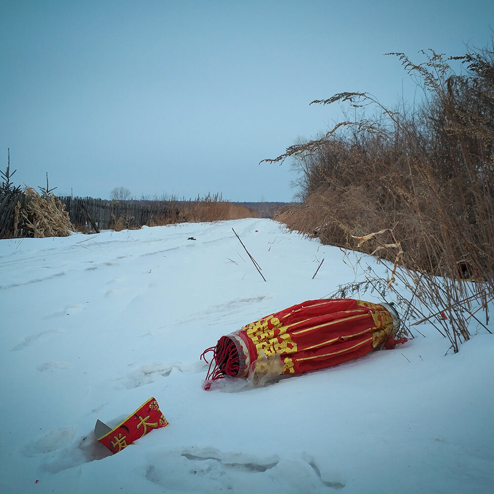 A discarded red lantern sits in the snow after Chinese New Year in Donglongshan.