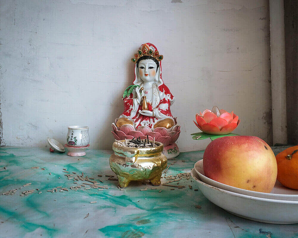 The grandmother’s statue of Guanyin, the goddess of mercy in Chinese Buddhism, with offerings of fruit.